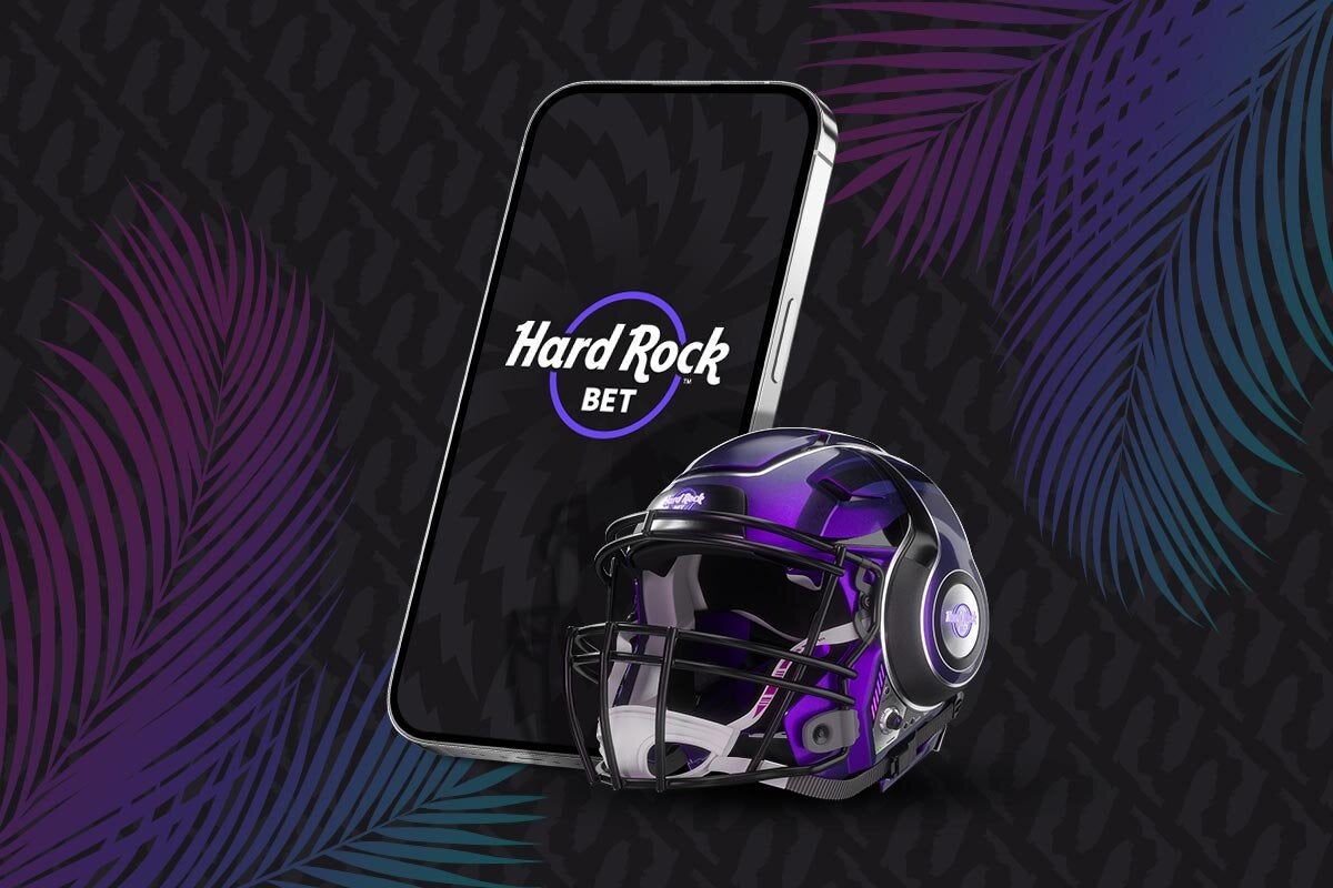 A cell phone with the Hard Rock Bet logo on the screen next to a football helmet